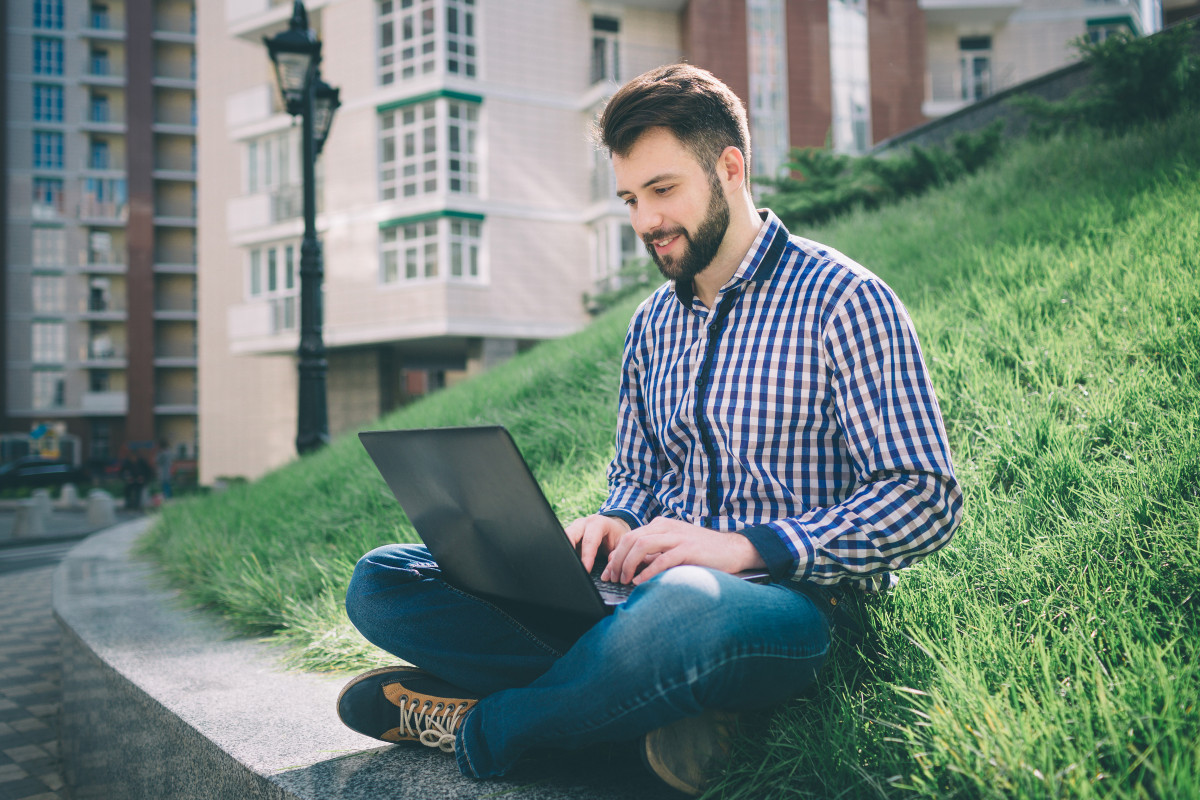 Junger Mann mit Laptop im Park